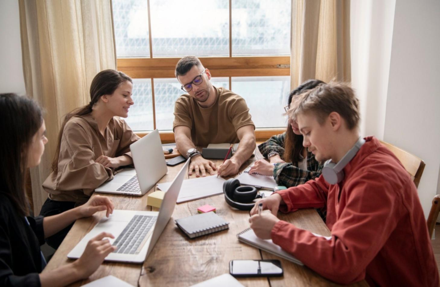 Gemeinsame Lernsituation mit Finanzunterlagen und Laptops auf einem Tisch